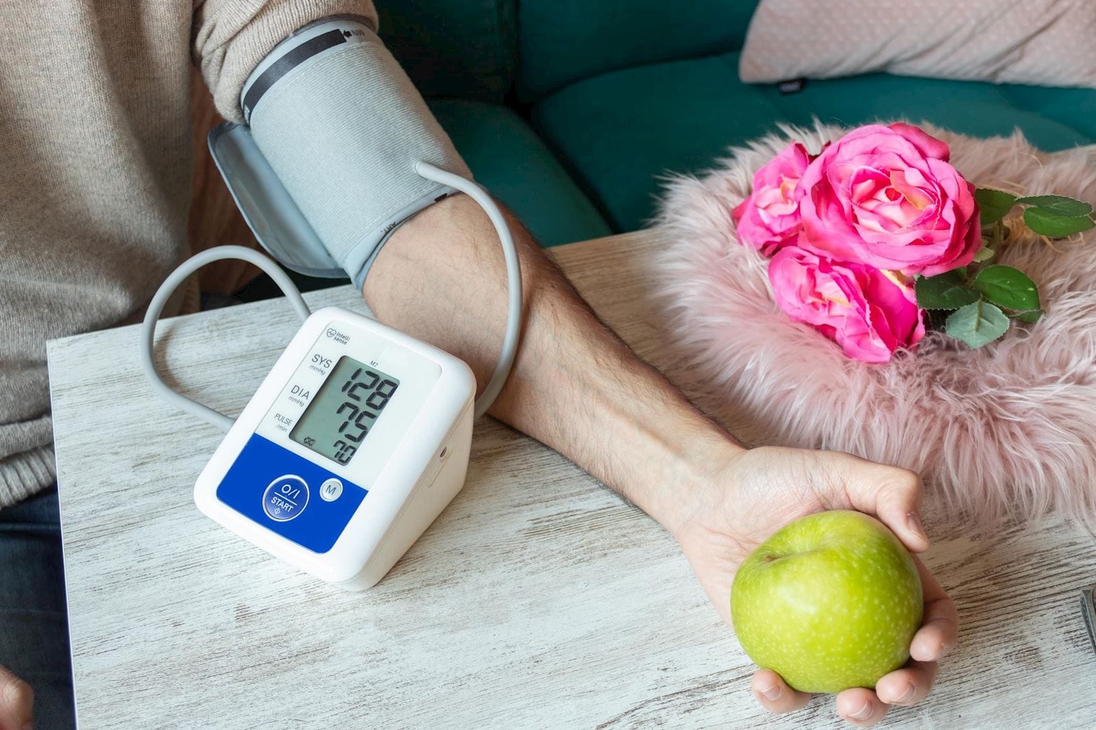 Man takes blood pressure with a cuff while holding an apple in his hand